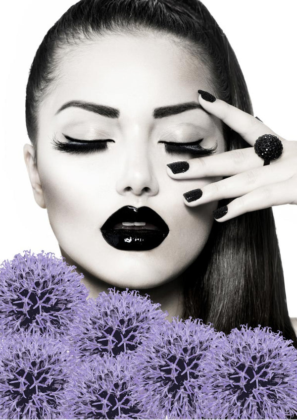 Stylish woman with black lips and nails, posing with hand near face, surrounded by purple flowers.