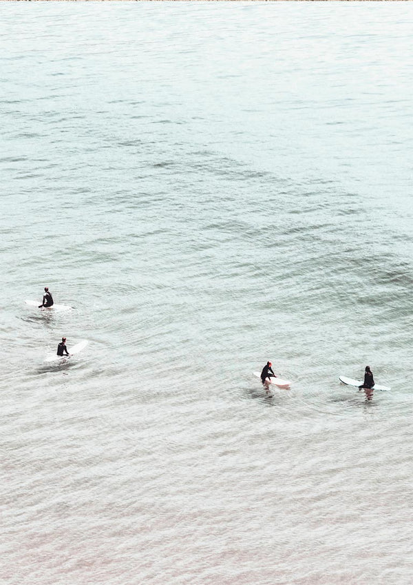 Four surfers on surfboards sit in calm, pale water seen from above for Surfers in Water Plakat.