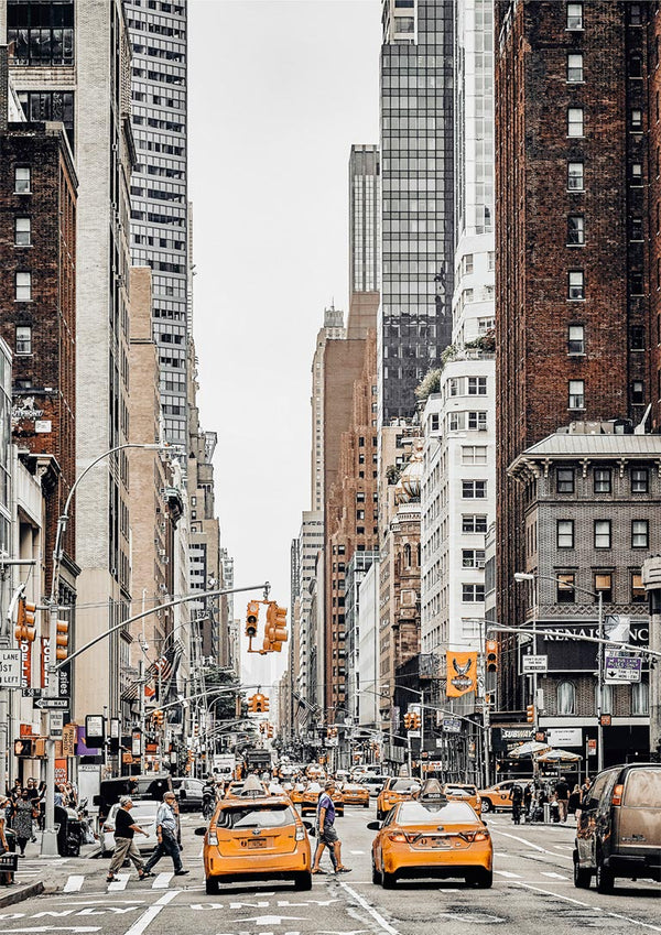 Yellow taxis and busy street scene surrounded by tall buildings in New York City.