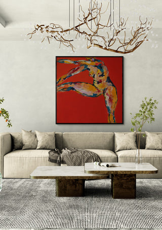 Arch in Red by René J in a black frame above a beige sofa under a branch chandelier