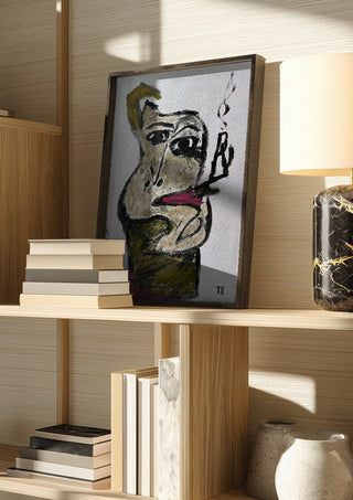 Pipan by RR in a dark frame on a wooden shelf beside books and a lamp
