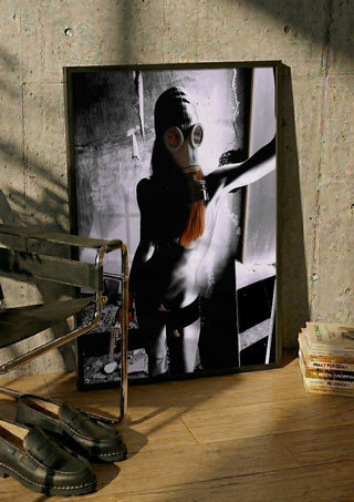 Beauty The Beast by Pelecan Schneider in a black frame leaning against a concrete wall by a steel chair