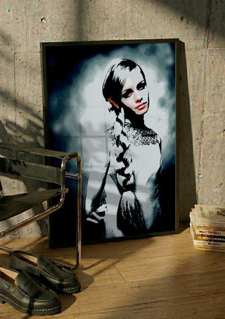 Twiggy by Pelecan Schneider in a black frame leaning against a concrete wall by a steel chair
