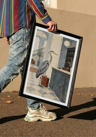 The Heron Checks In by Matthews Gallerie carried in a black frame along a sunny street