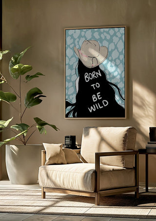 Born to be wild by Lisen Vennesland framed above a beige armchair beside a potted plant