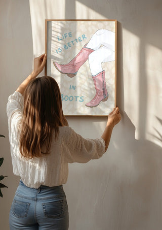 Life is better in boots by Lisen Vennesland being hung on a sunlit wall