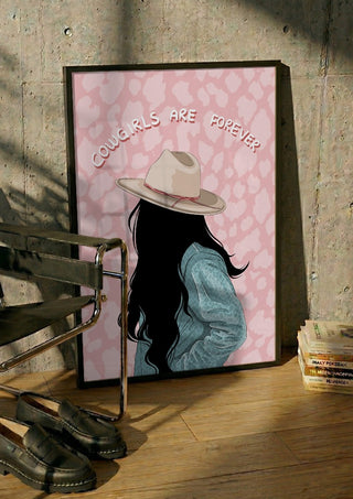 Cowgirls are forever by Lisen Vennesland in a black frame leaning against a concrete wall by a steel chair