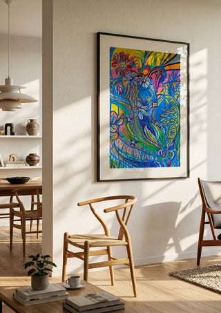 Garden Party by Da Winters in a black frame in a bright dining room with wooden chairs