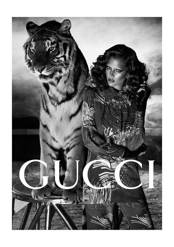 Black and white poster of a woman posing with a tiger, featuring GUCCI logo for the Tiger Fashion collection.