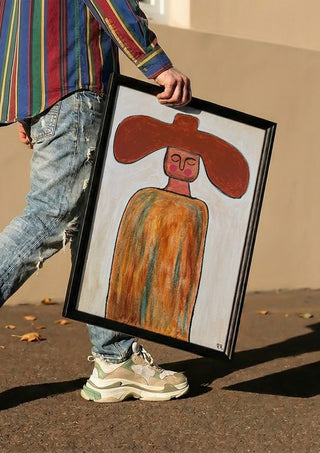 Cowboy by RR carried in a black frame along a sunny street