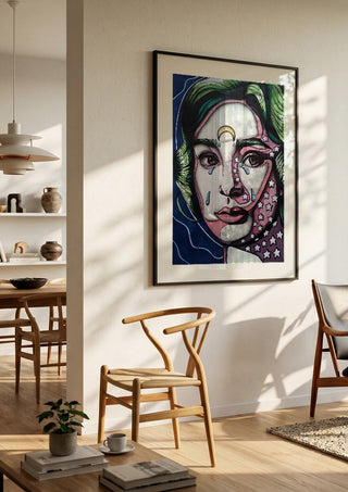 Audrey Hepburn by Okiana in a black frame in a bright dining room with wooden chairs