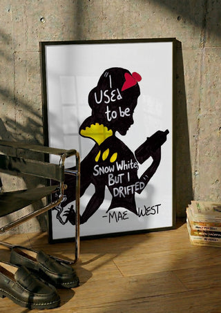 I Used to Be Snow White by Camilla Nilsson in a black frame leaning against a concrete wall by a steel chair