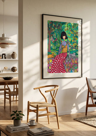 The Garden Wall by Camilla Nilsson in a black frame in a bright dining room with wooden chairs