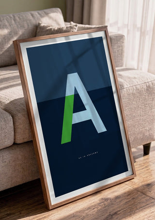 A as in Awesome – Blue by Quite Nice Prints in a walnut frame leaning against a grey sofa