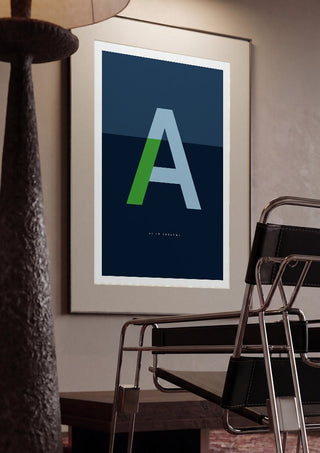 A as in Awesome – Blue by Quite Nice Prints framed in a dim room beside a tubular steel chair