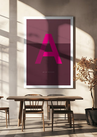 A as in Awesome – Cerise by Quite Nice Prints hanging above a wooden dining table in warm sunlight
