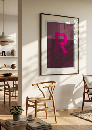 R as in Rebel – Cerise by Quite Nice Prints in a black frame in a bright dining room with wooden chairs