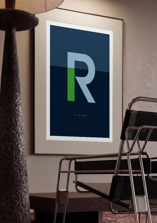 R as in Rebel – Blue by Quite Nice Prints framed in a dim room beside a tubular steel chair