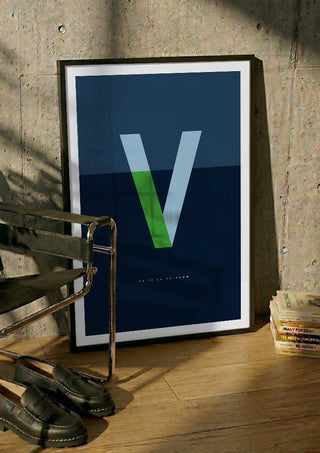V as in Va-va-voom – Blue by Quite Nice Prints in a black frame leaning against a concrete wall by a steel chair