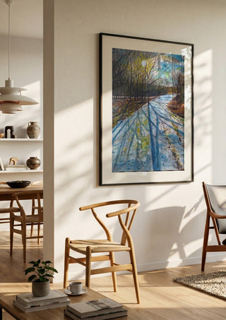 Shadows of the Day by Finbar Stevens in a black frame in a bright dining room with wooden chairs