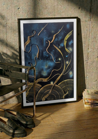 Gold Ribbons at Night by luco art in a black frame leaning against a concrete wall by a steel chair