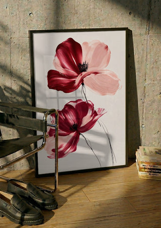 Crimson and Blush by Martina Karlsson in a black frame leaning against a concrete wall by a steel chair