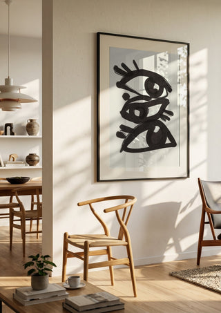 Abstract line art eyes 3 by ThingDesign in a black frame in a bright dining room with wooden chairs