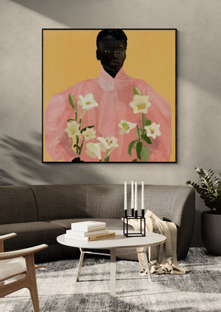 Girl Holding Flowers 2 by ThingDesign in a black frame above a curved grey sofa with candlesticks on a round table