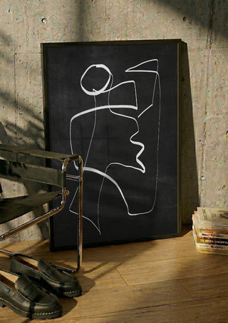 Form in Motion by ThingDesign in a black frame leaning against a concrete wall by a steel chair