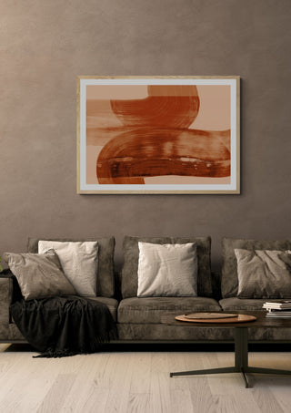 abstract shapes - autumn orange by Iris Lehnhardt in a light oak frame above a grey sofa on a warm brown wall