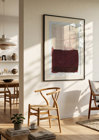 colorfields pale pink warm red by Iris Lehnhardt in a black frame in a bright dining room with wooden chairs