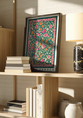 Vie de Jardin by Annika Persson in a dark frame on a wooden shelf beside books and a lamp