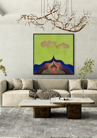 Mountain Under a Green Sky by Shimmering Ugly in a black frame above a beige sofa under a branch chandelier