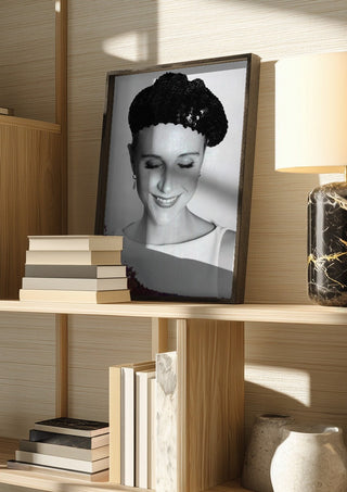 The French girl by Bettinafloorphoto in a dark frame on a wooden shelf beside books and a lamp