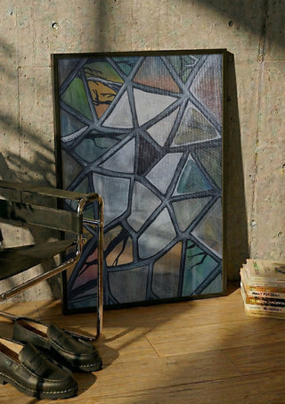 Cracked Glass by Fredprikas in a black frame leaning against a concrete wall by a steel chair