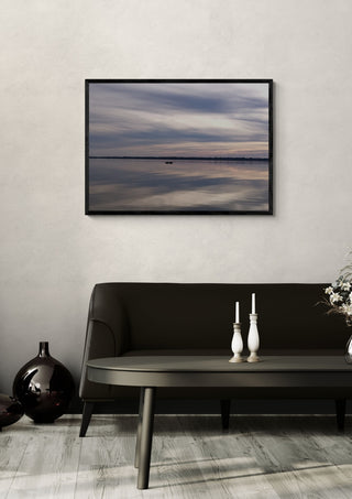 Dusk Reflections by Bora Kőhalmi in a black frame on a pale wall above a dark sofa with candlesticks