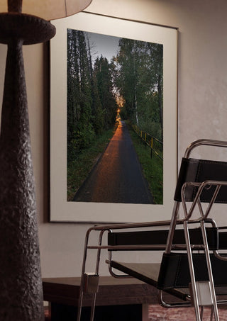The Amber Forest Path by Bora Kőhalmi framed in a dim room beside a tubular steel chair