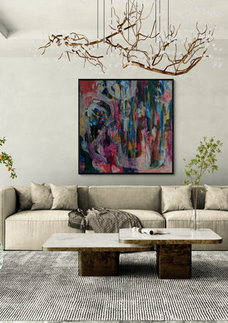 All Roads Lead Home by Janet Bell in a black frame above a pale sofa under a branch chandelier