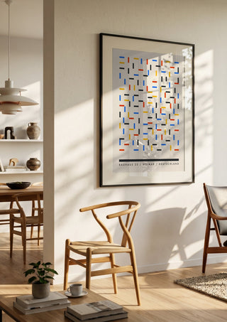 Bauhaus Dashes by Neil Stevens in a black frame in a bright dining room with wooden chairs