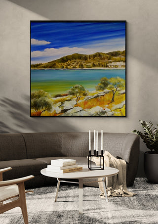 Dalmatia by Sunny in a black frame above a grey sofa with a round table and candlesticks
