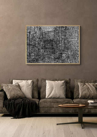 Hesburger by Priit Ruttas in a pale wooden frame above a grey sofa with cushions