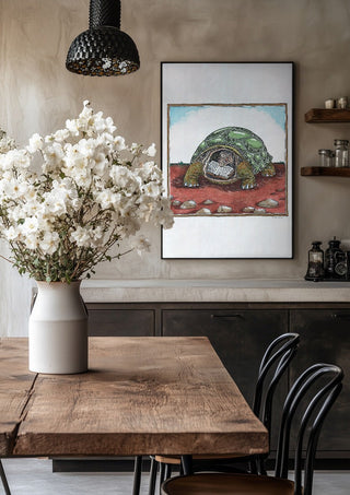 The Reading Tortoise by Waldemar Mandzel in a black frame above a rustic table with white flowers