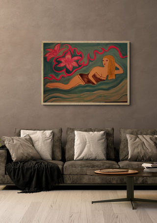 Lying Blonde by Carmen Coduri in a pale wooden frame above a grey sofa with cushions