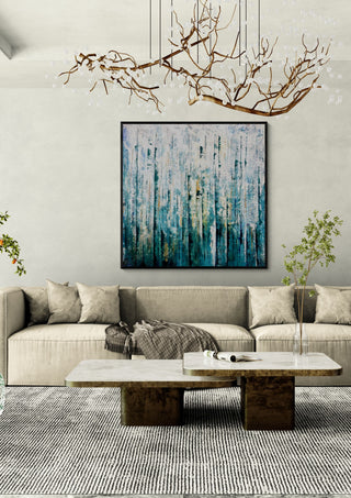 Teal Abstract by Marina Agre in a black frame above a beige sofa under a branch chandelier