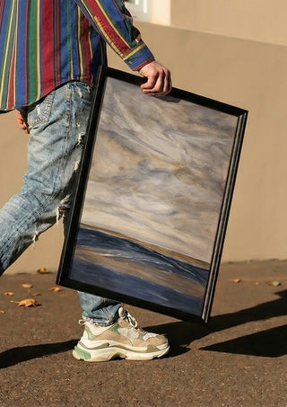 Whispers of Silence by Maya carried in a black frame along a sunny street