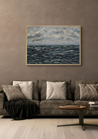Beyond the storm by Maya in a pale wooden frame above a grey sofa with cushions