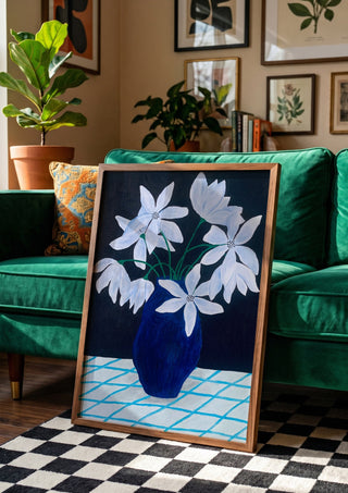 Blå blomster på rutig duk by Rebecka Hansson in a wooden frame leaning against a green velvet sofa on a chequered floor