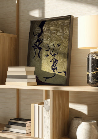 Whispers in Gold by Bibi in a dark frame on a wooden shelf beside books and a lamp
