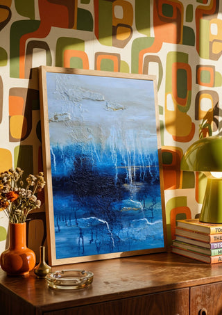 Rising Light by Sabine Halbrock in a wooden frame on a sideboard against retro patterned wallpaper