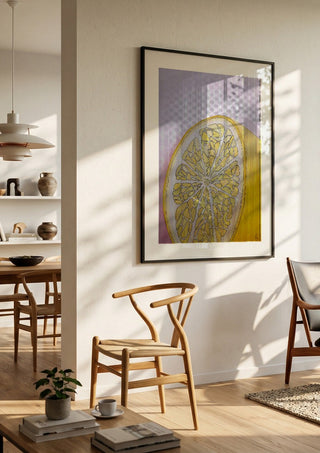 Half Lemon by L.OE. Art in a black frame in a bright dining room with wooden chairs